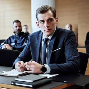 Näyttelijä Lauri Tilkanen sarjan kuvauksissa oikeussalissa.