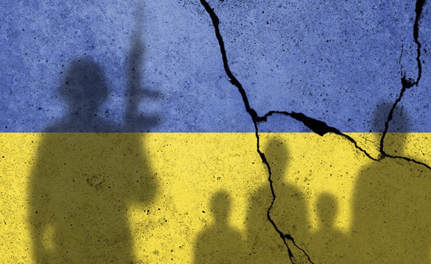 Seinä, johon on maalattu Ukrainan lippu ja johon heijastuu sotilaan ja siviilien varjoja.